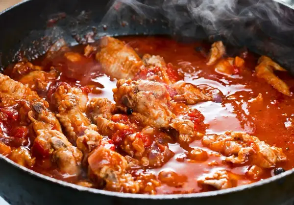 Succulenta carne alla pizzaiola che sobbolle in padella, sprigionando un profumo invitante. Pezzi di carne tenera immersi in un sugo rosso ricco di pomodoro e spezie.