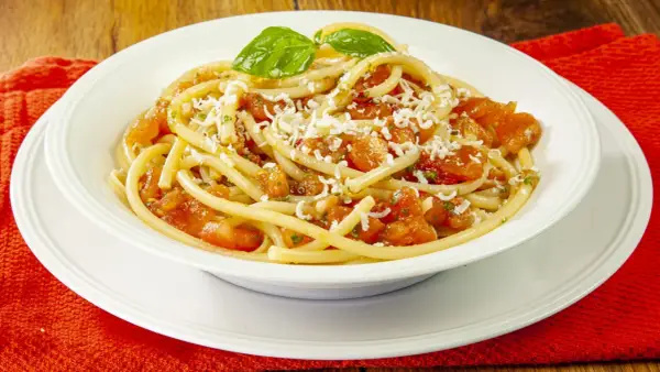 Un piatto invitante di pasta alla carrettiera, con pomodoro fresco, basilico e abbondante formaggio grattugiato.