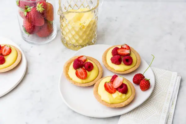Deliziose tartellette alla frutta con crema pasticcera e frutti di bosco freschi, pronte per essere gustate.