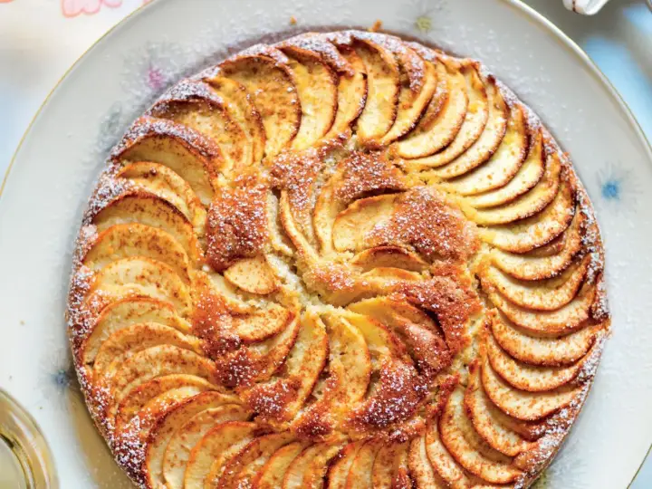 Una deliziosa torta di mele, con fette disposte a raggiera e una spolverata di zucchero a velo.